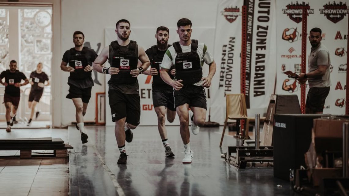 Group of men running in an indoor fitness competition, showcasing athleticism and determination.