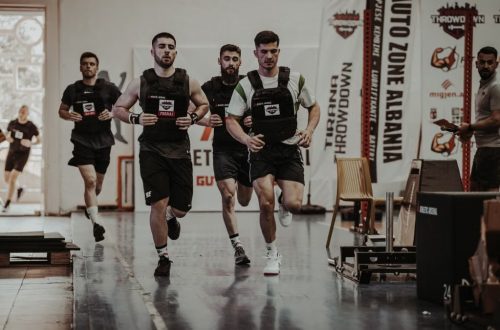 Group of men running in an indoor fitness competition, showcasing athleticism and determination.