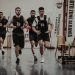 Group of men running in an indoor fitness competition, showcasing athleticism and determination.